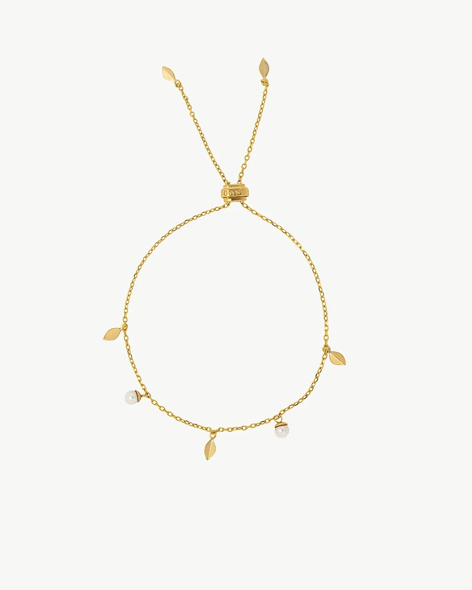 Vista cenital de pulsera ajustable dorada con perlas y hojas, dispuesta en círculo sobre fondo blanco.