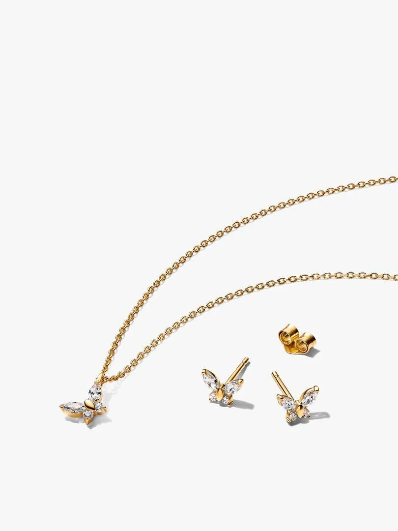 Gouden vlinderketting en oorknopjes met zirkonia, gerangschikt op een witte achtergrond.