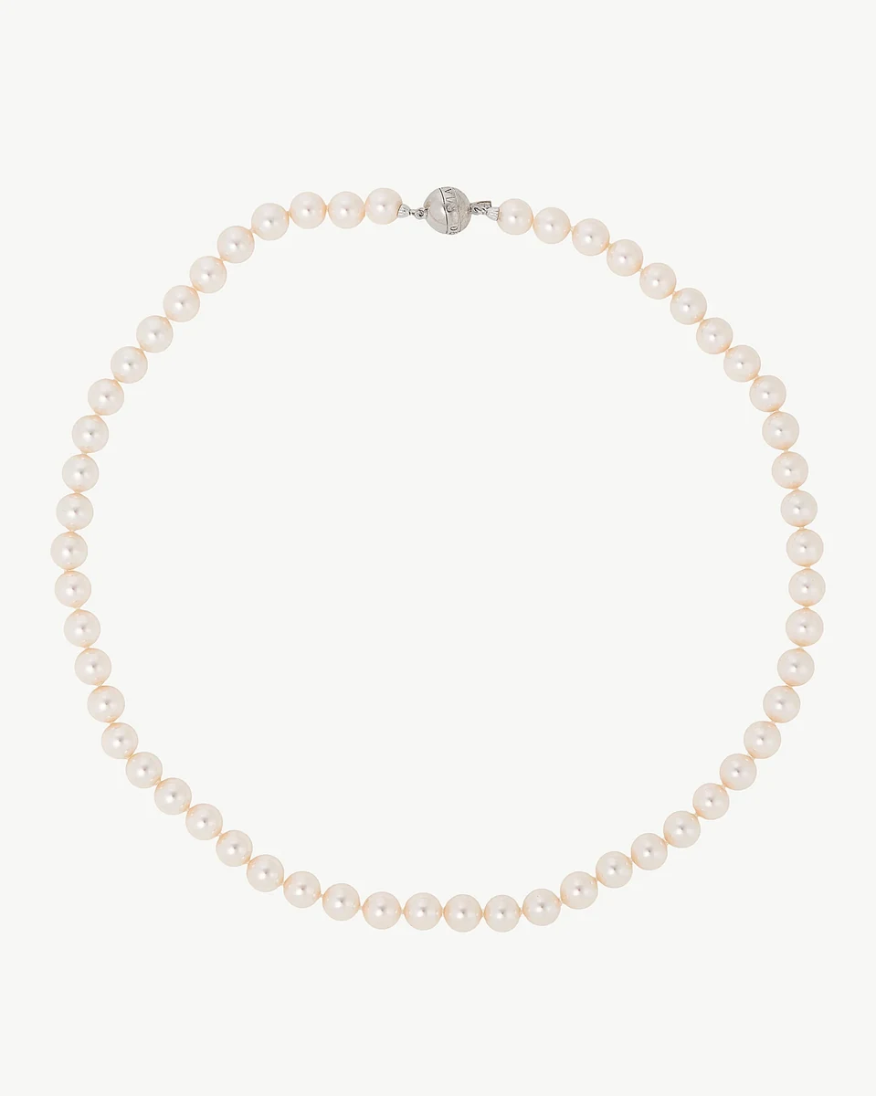 Collier de perles disposé en cercle sur fond blanc, vue de face avec fermoir en argent visible.