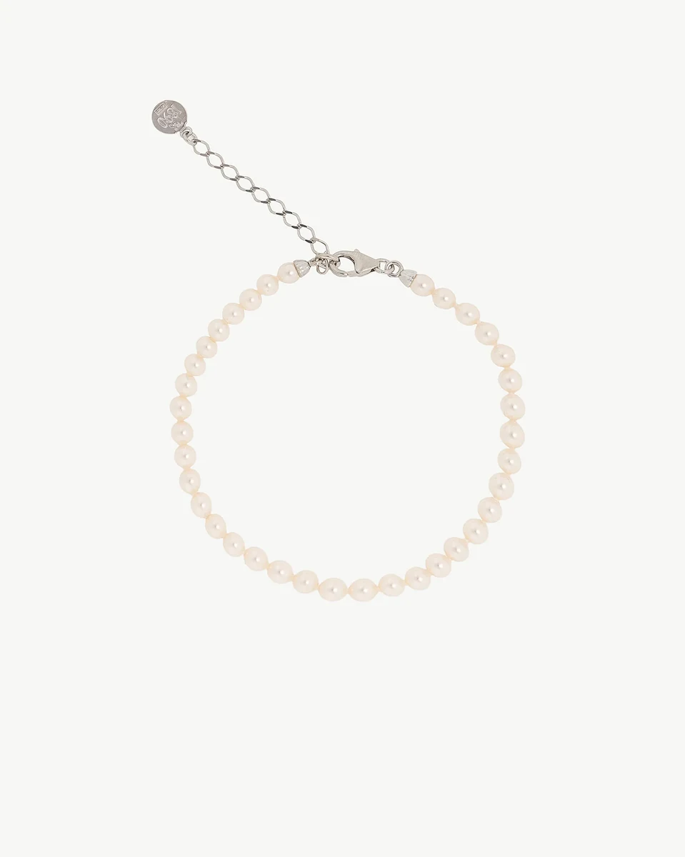 Pearl bracelet arranged in a circle on a white background, top view showing clasp and extender chain.