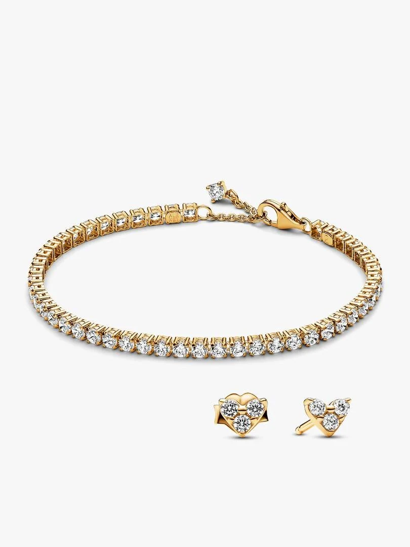Pulsera tenis y pendientes de corazón sobre fondo blanco, vista frontal con ángulo ligeramente picado.