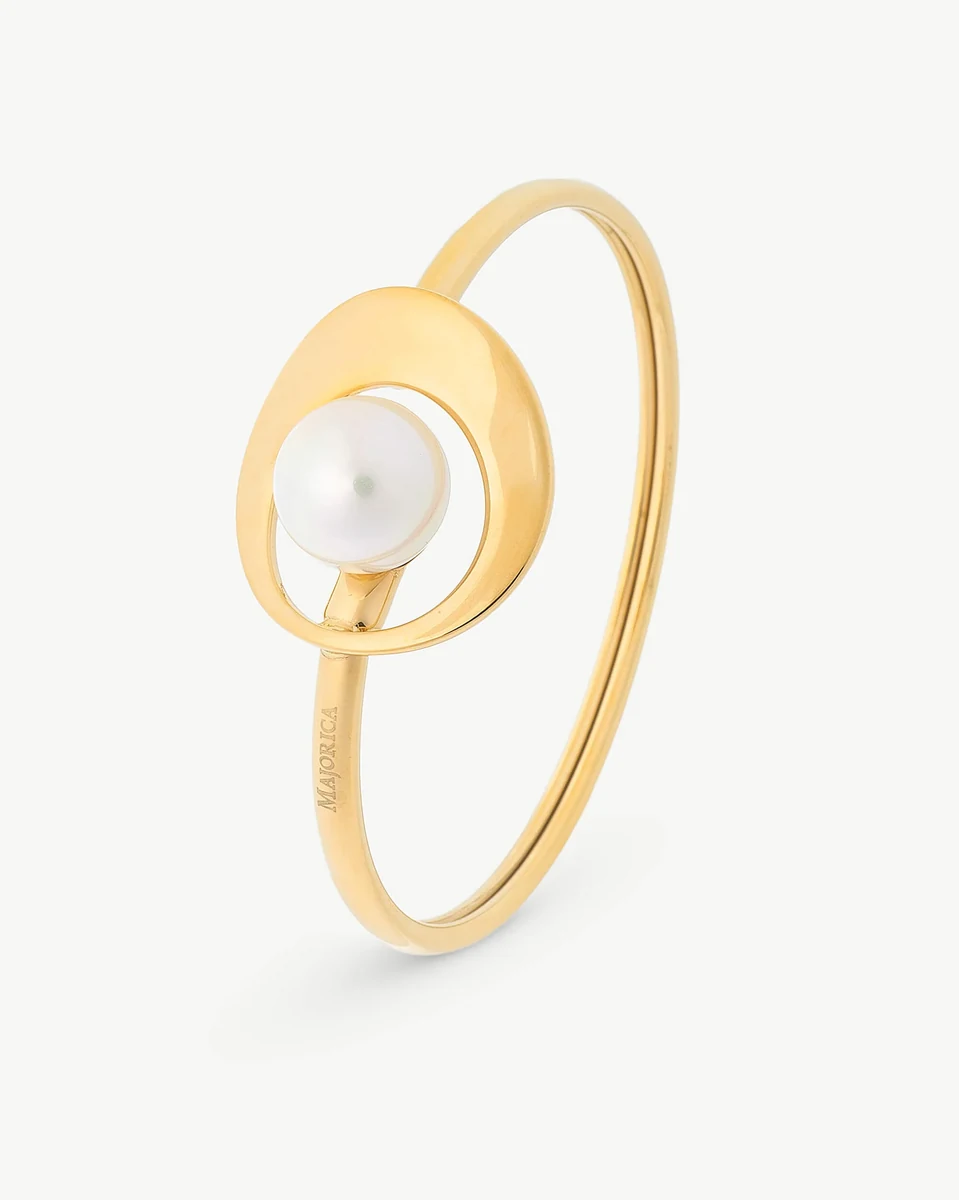 Bracelet jonc doré avec perle blanche centrale, vue de profil en angle sur fond blanc.