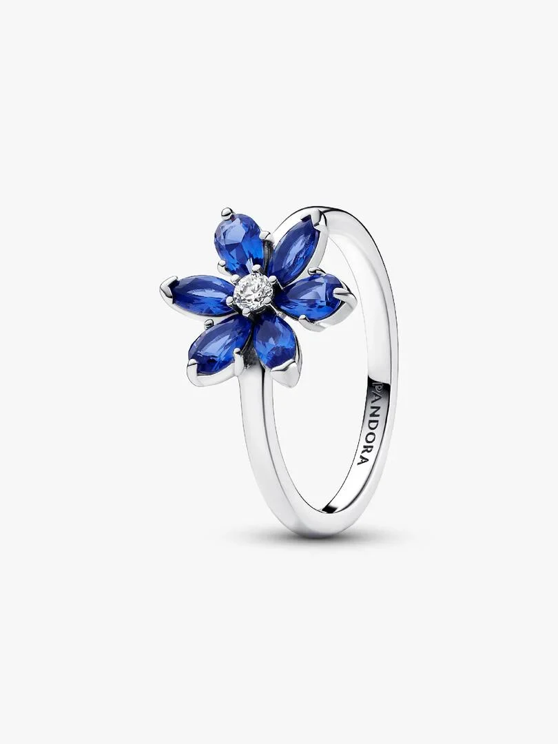 Side angle view of a floral ring with blue stones and clear center on a white background.