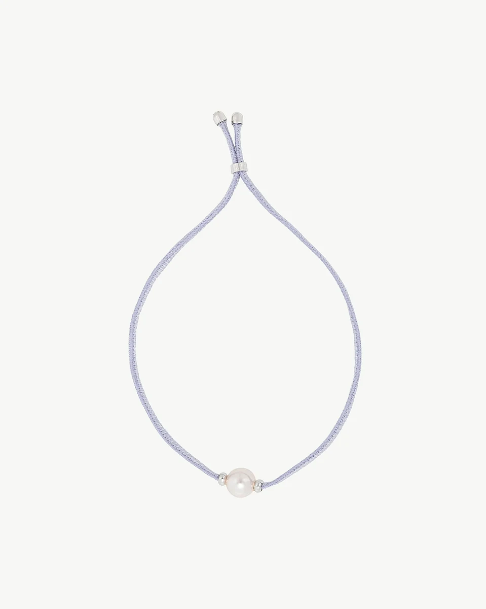 Top view of blue cord bracelet centered on white background, featuring a white pearl and adjustable clasp.