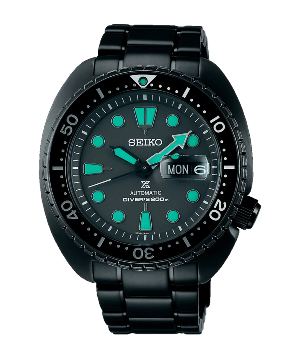 Vista frontal completa de reloj negro con índices luminiscentes verdes sobre fondo blanco.