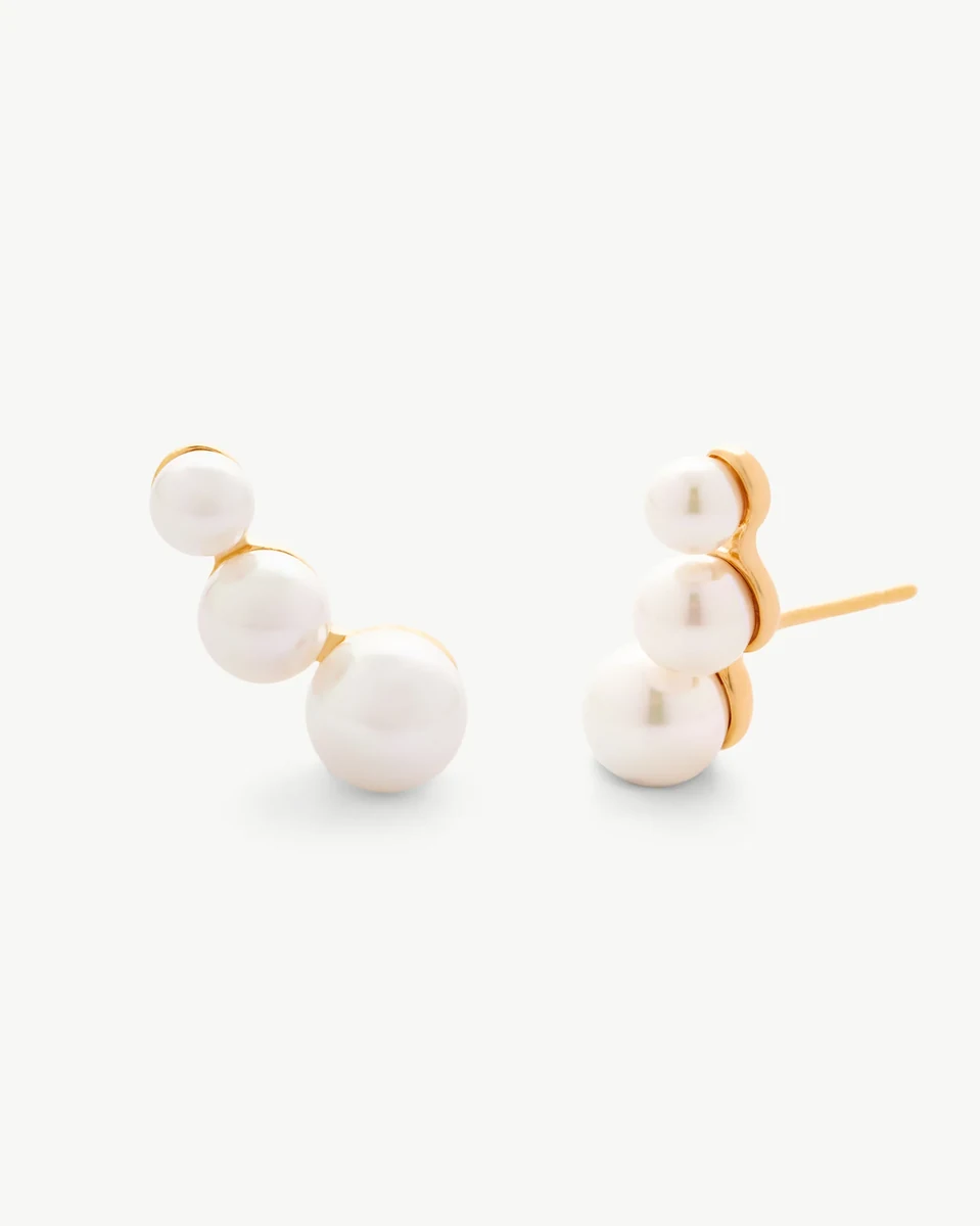 Par de pendientes trepadores con tres perlas blancas sobre fondo blanco, vista frontal ligeramente inclinada.