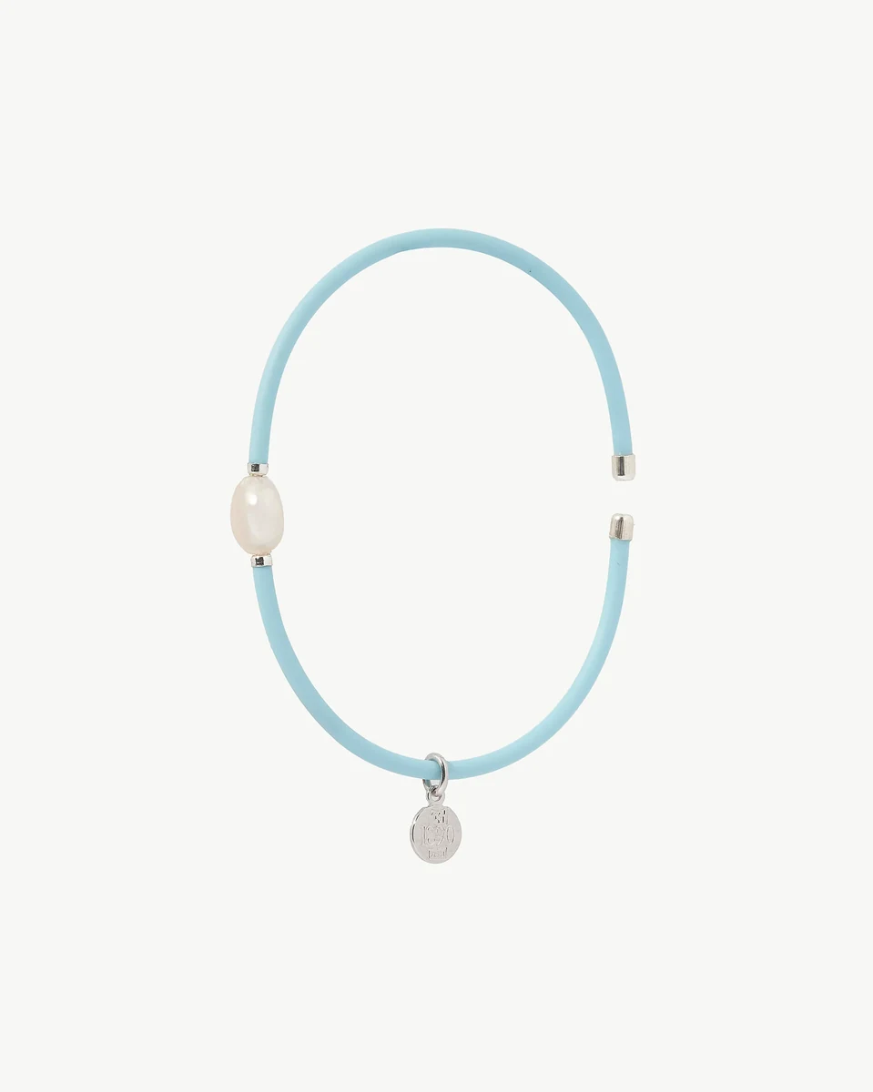 Brazalete azul con perla blanca y dije circular, vista frontal sobre fondo blanco.