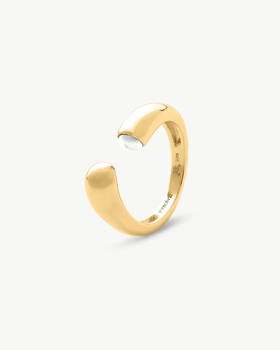 Bague ouverte dorée vue de profil avec une demi-perle blanche, sur fond blanc.