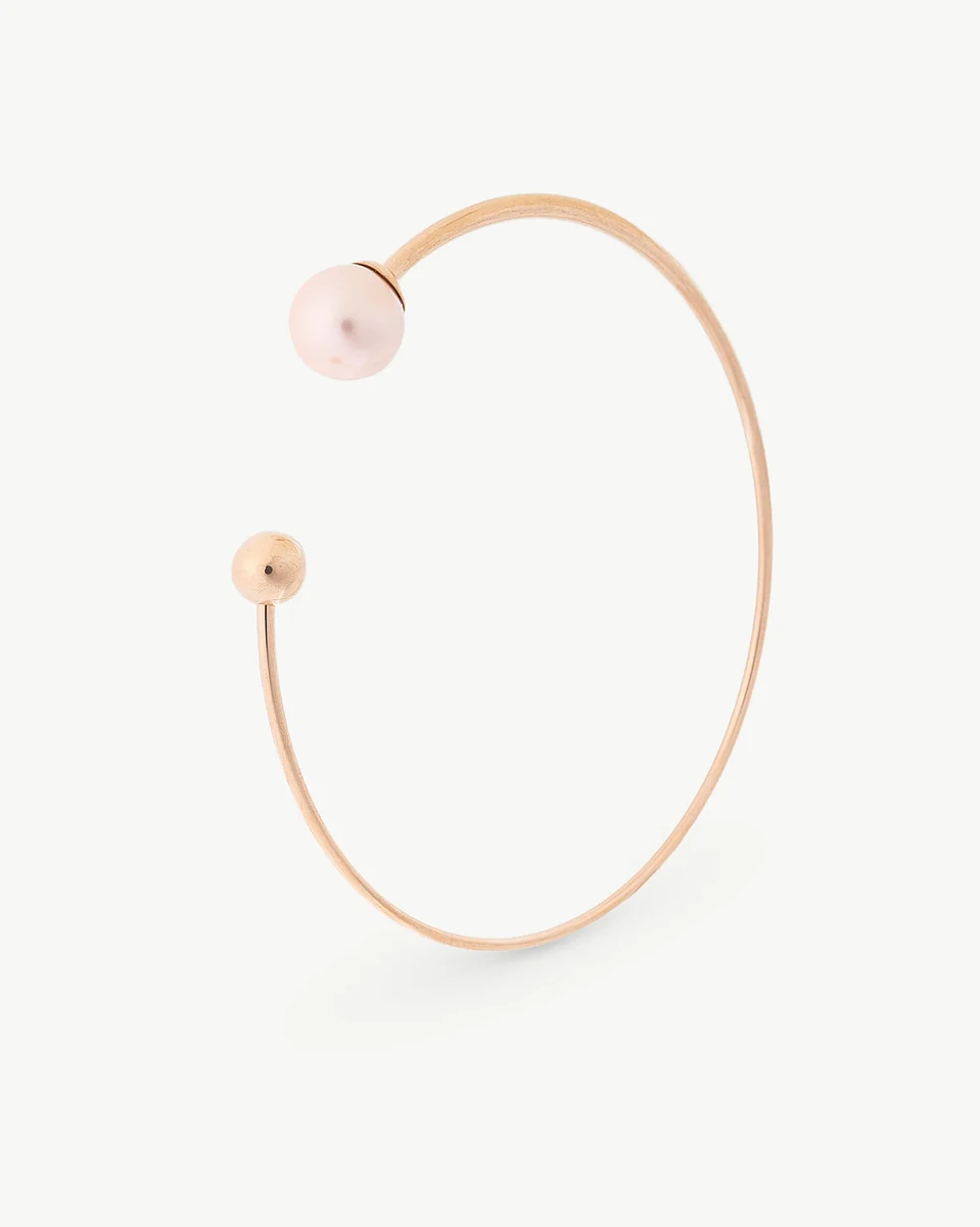 Bracelet jonc en acier rose avec perle, vue de profil sur fond blanc.