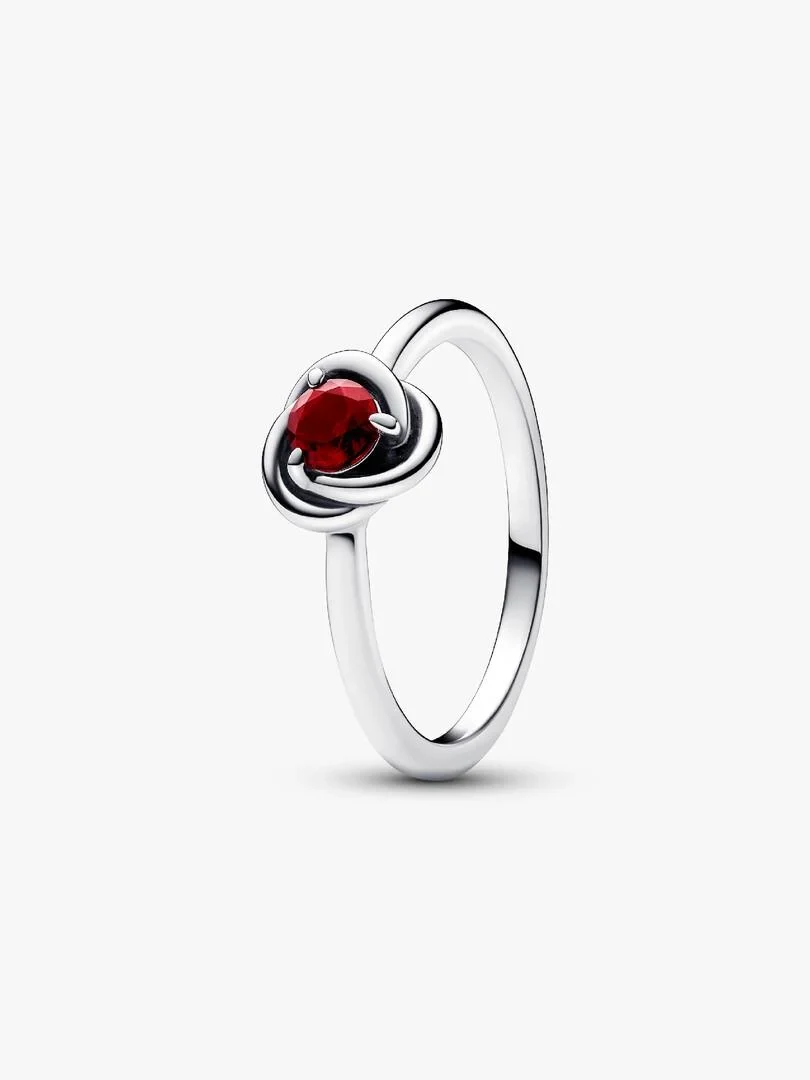 Anillo de plata con cristal rojo visto en ángulo lateral, sobre fondo blanco puro.