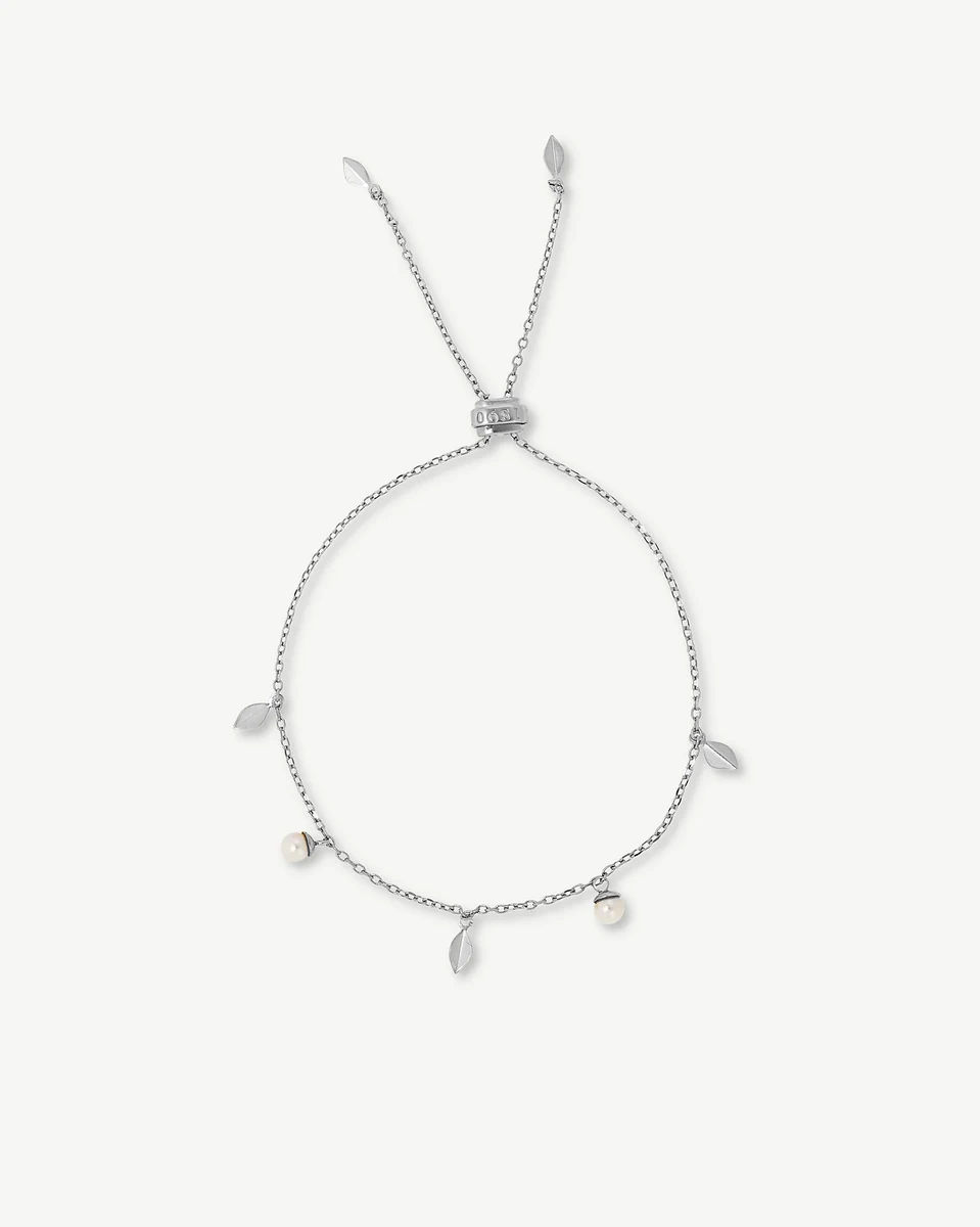 Zilveren armband met blaadjes en parels in een cirkel op een witte achtergrond, bovenaanzicht.