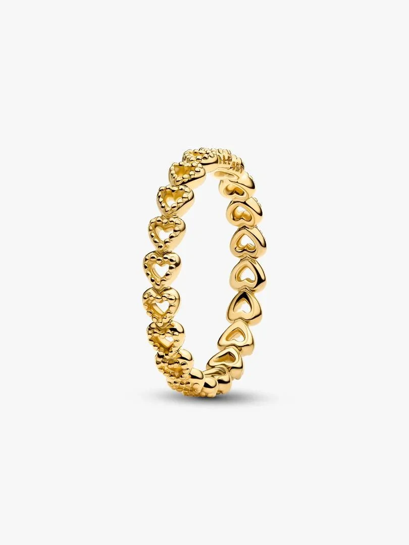 Anillo de banda con corazones en filigrana, vista lateral inclinada sobre fondo blanco.