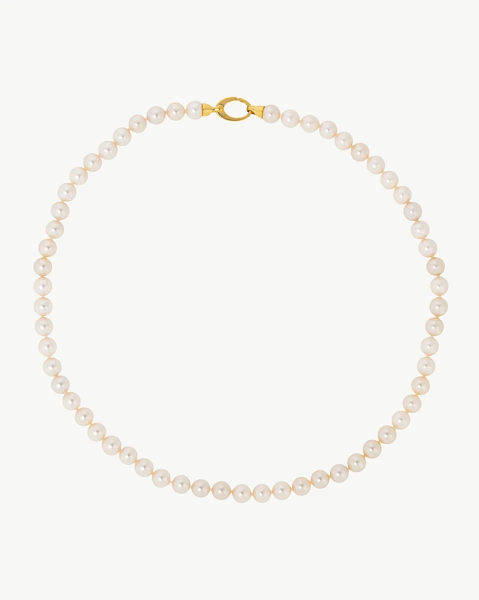 Collier de perles disposé en cercle sur fond blanc, vue de face avec fermoir doré visible.