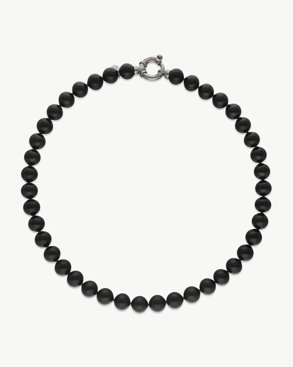 Black pearl necklace arranged in a circle on a white background, top view showing silver clasp.