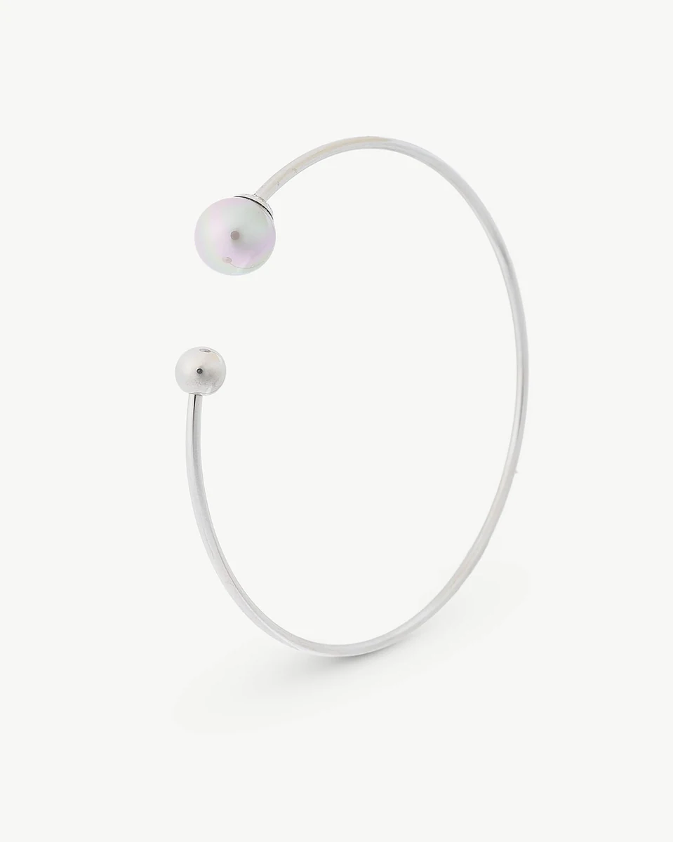 Bracelet en acier vu de profil, fond blanc, gros plan sur la perle Nuage et le terminal sphérique.