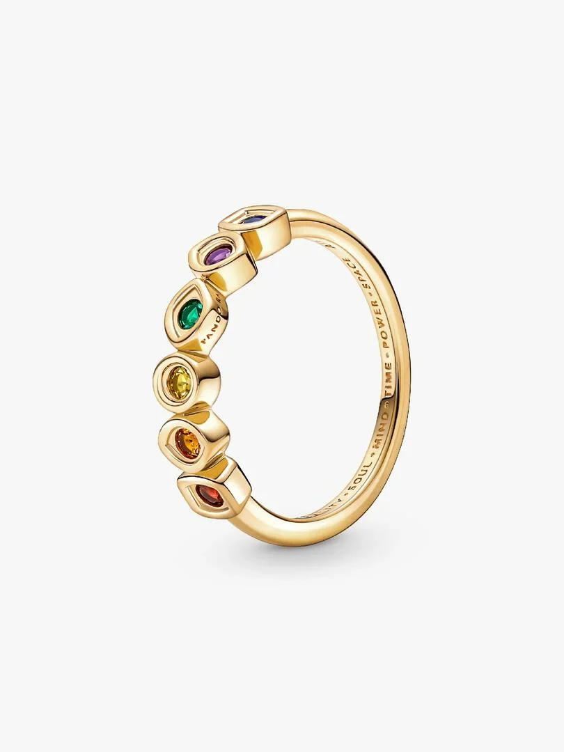 Anillo de oro con seis cristales de colores visto en ángulo lateral, fondo blanco, detalle del grabado interior.