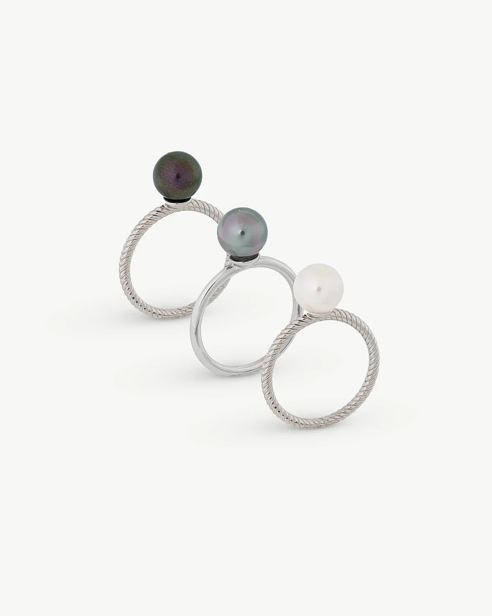 Vue de face de trois bagues en argent avec perles, disposées en diagonale sur fond blanc.