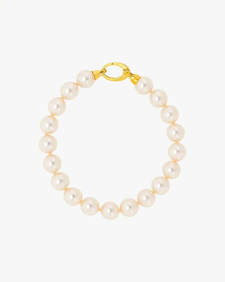Pearl bracelet arranged in a circle on a white background, top view showing the gold clasp detail.