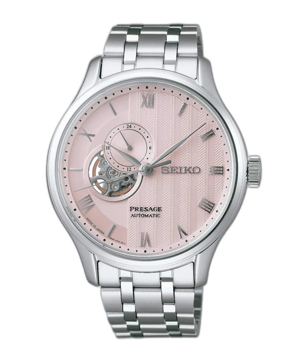 Vista frontal del reloj sobre fondo blanco, destacando la esfera rosa texturizada y el brazalete de acero inoxidable.