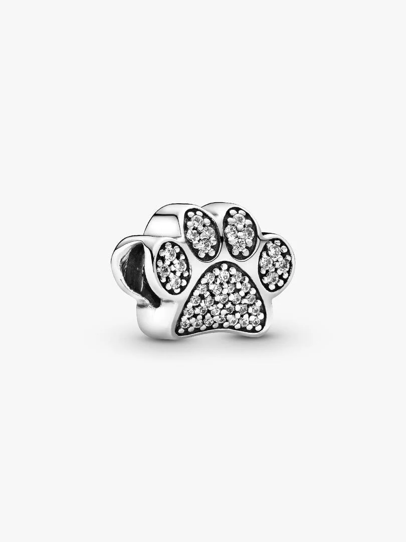 Silver paw print charm with cubic zirconia, side angle view on a white background.