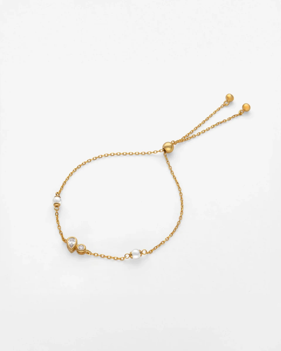 Goldene Armband in Kreisform auf weißem Hintergrund, Draufsicht mit Details von Perlen und Zirkonia.