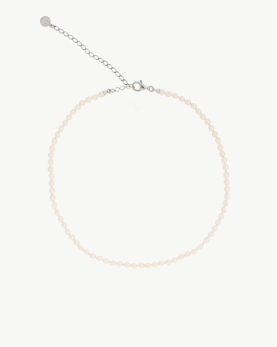 Pearl necklace arranged in a circle on a white background, front view showing clasp and extender chain.