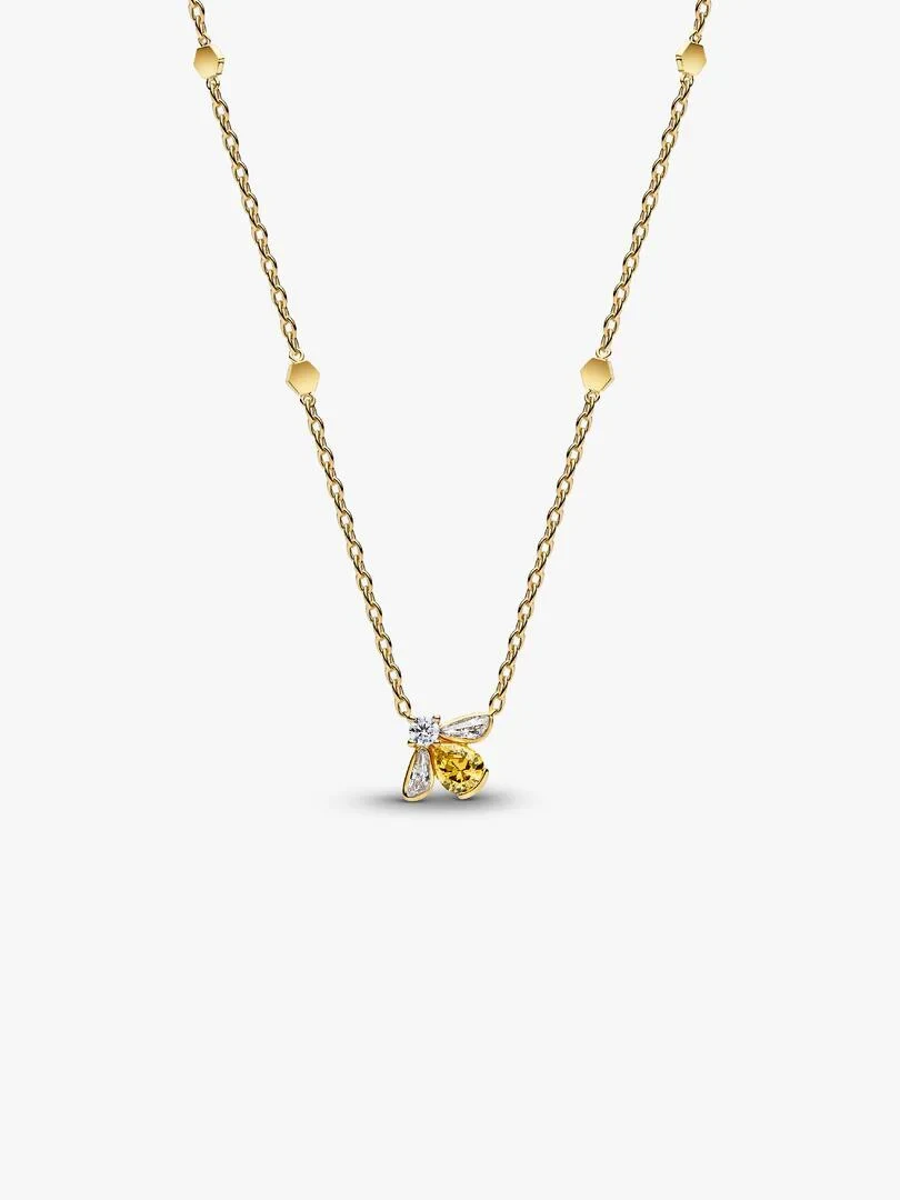 Collier avec pendentif abeille jaune et détails hexagonaux sur chaîne dorée, fond blanc.