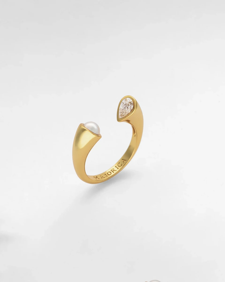 Offener Goldring in Seitenansicht, weißer Hintergrund, Detail der halben Perle und Zirkonia.