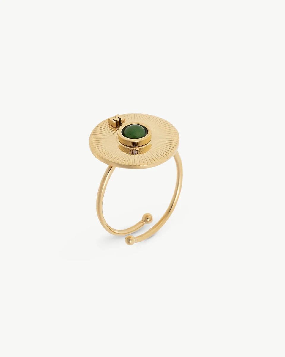 Anillo ajustable de acero dorado con media perla verde, vista lateral en ángulo sobre fondo blanco.