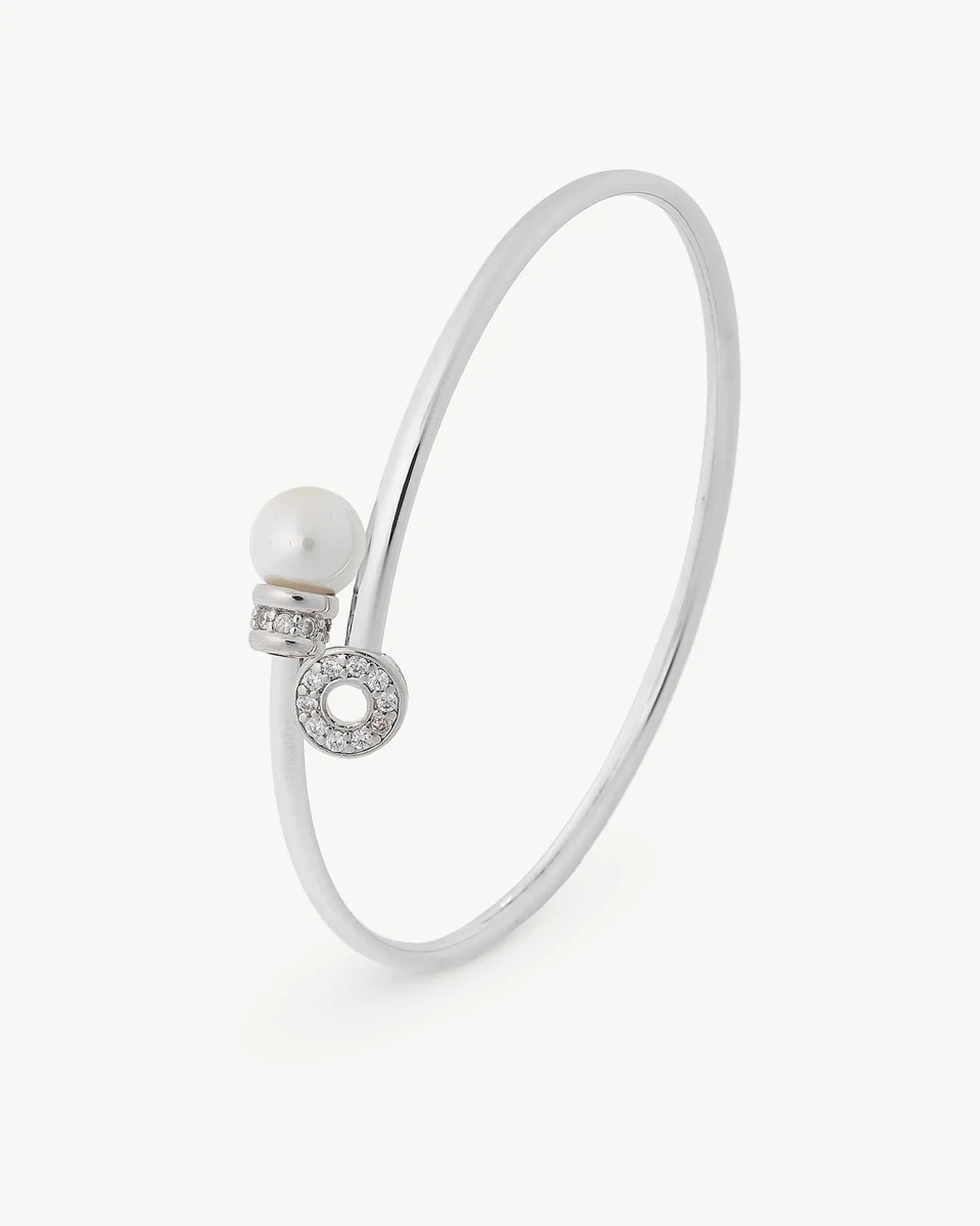 Brazalete rígido de plata con perla y circonitas, vista lateral en ángulo sobre fondo blanco.