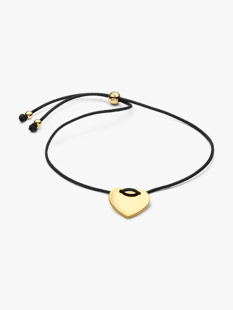 Bracelet cordon noir avec pendentif cœur doré, vue de face inclinée sur fond blanc.