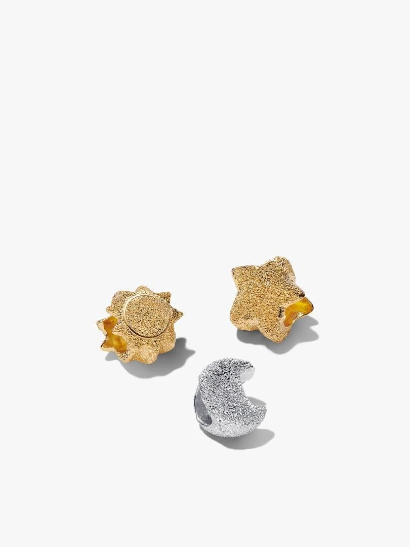 Bovenaanzicht van drie hemelse charms op een witte achtergrond, met de zon, maan en ster.