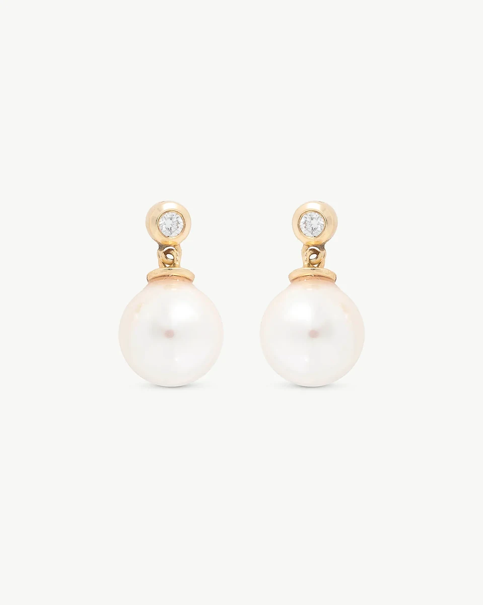 Front view of pearl and diamond earrings on a white background, symmetrical shot.